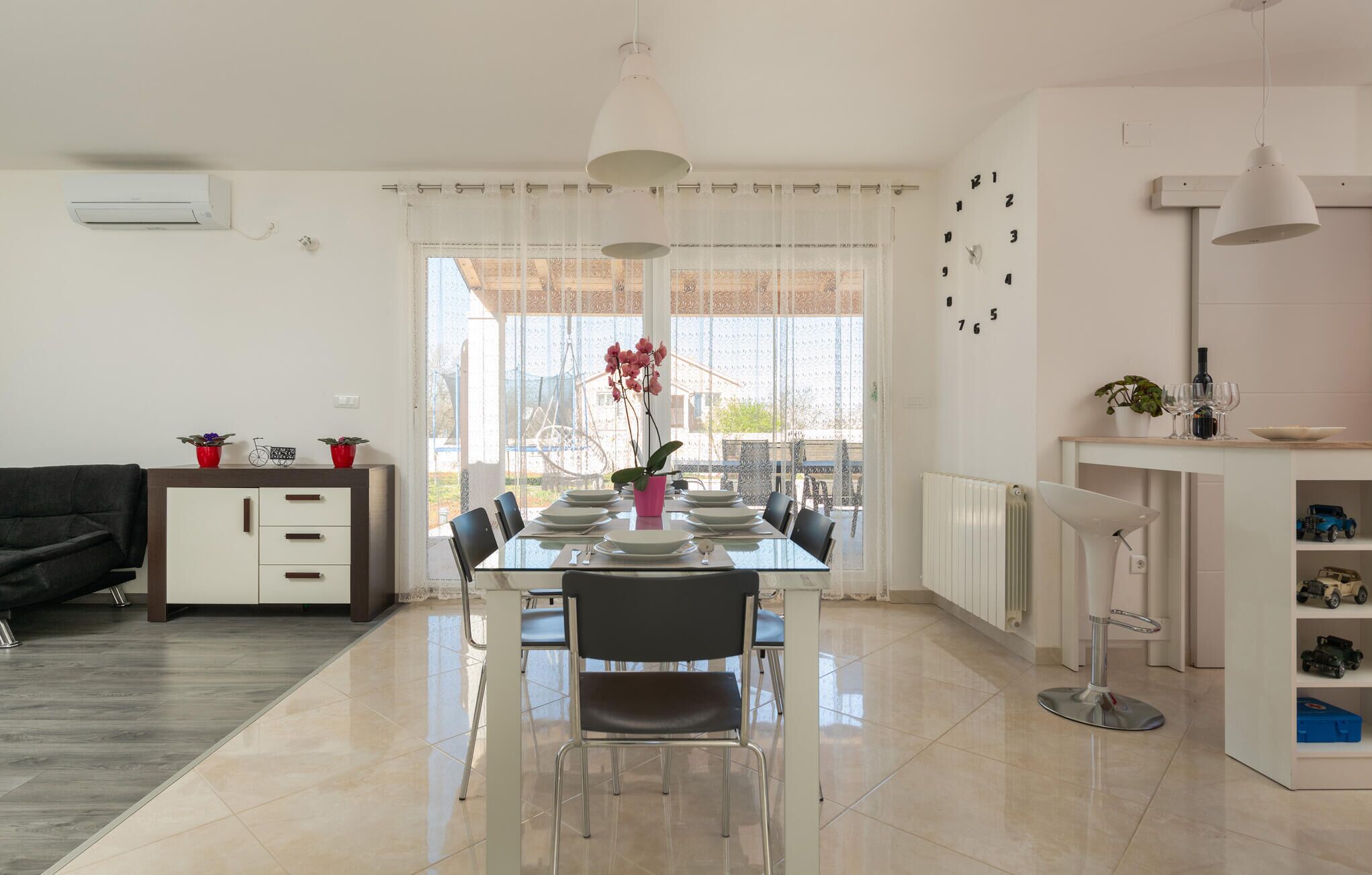 A modern dining area with a glass table, chairs, and a view of the outdoors.