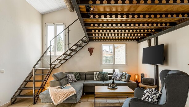 A modern living room with a staircase, a sofa set, a coffee table, and a TV mounted on the wall.