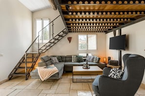 Uma sala de estar moderna com escada, sofá, mesa de centro e TV na parede.