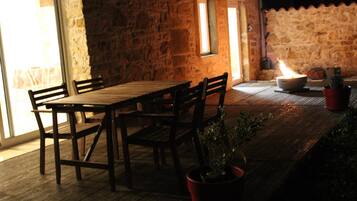 Un tavolo in legno all'aperto con sedie, un muro in pietra e una borsa fuoco.