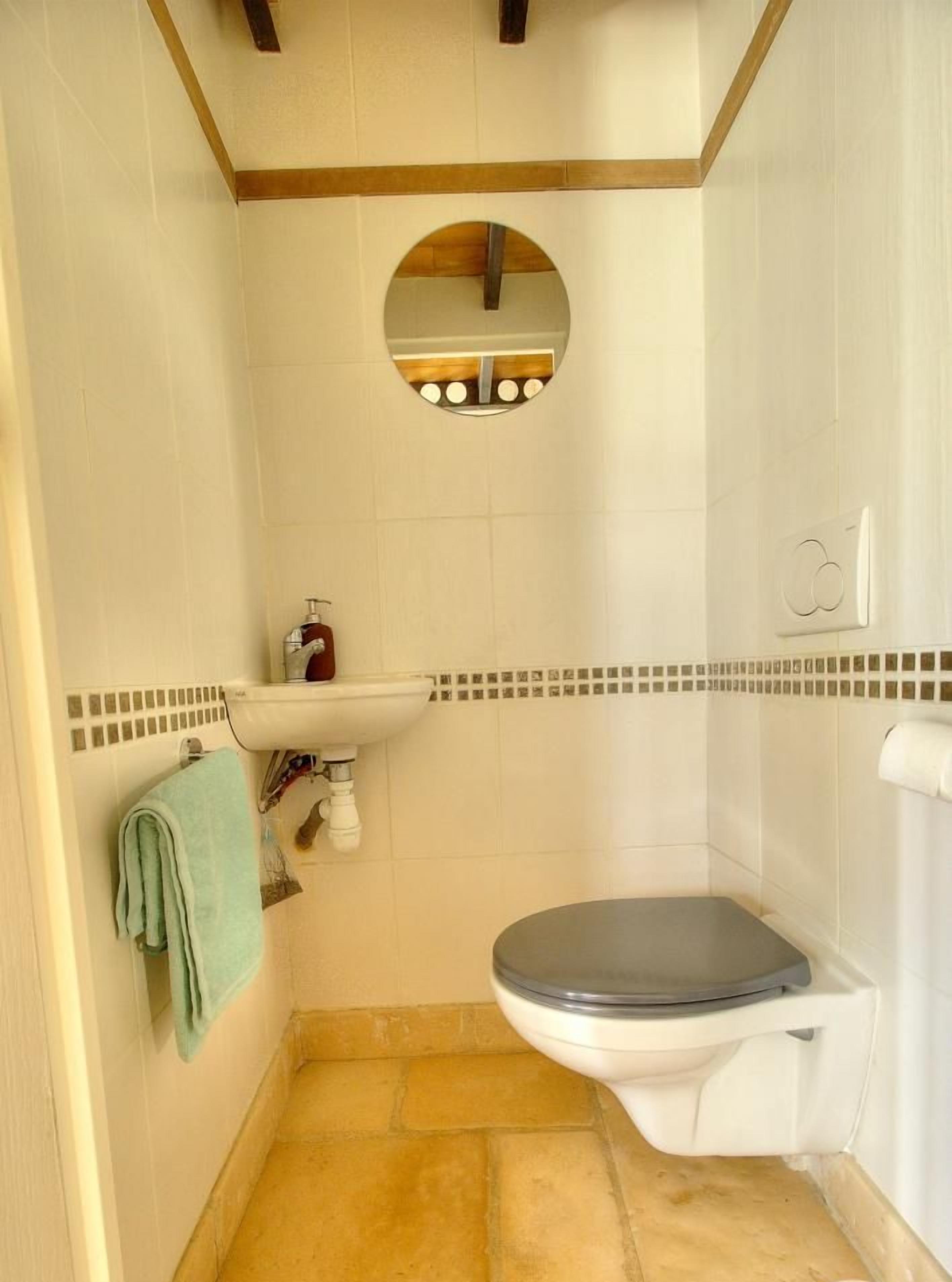 Een badkamer met toilet, wastafel en spiegel.