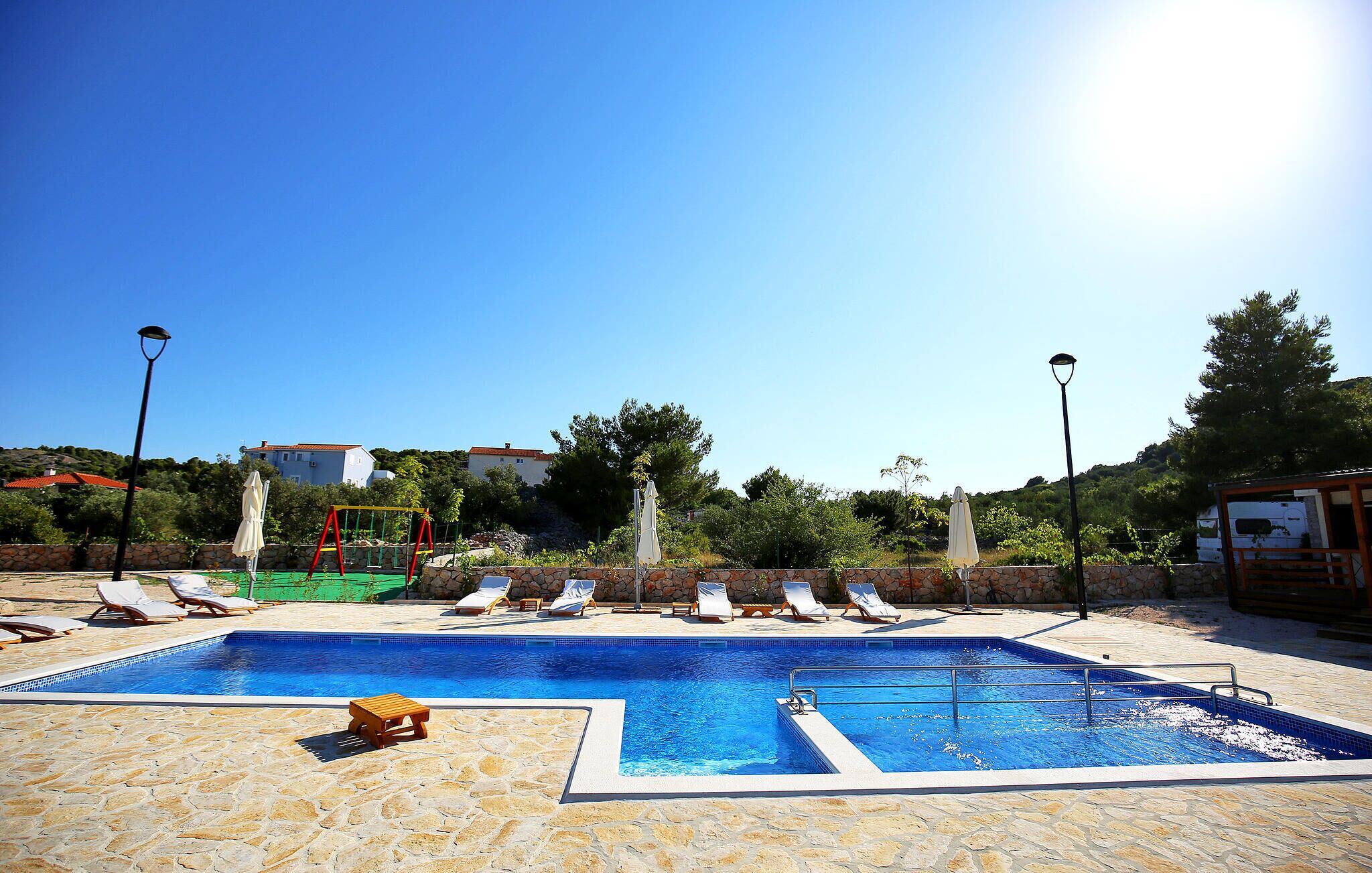 A swimming pool with lounge chairs and a children's play area.