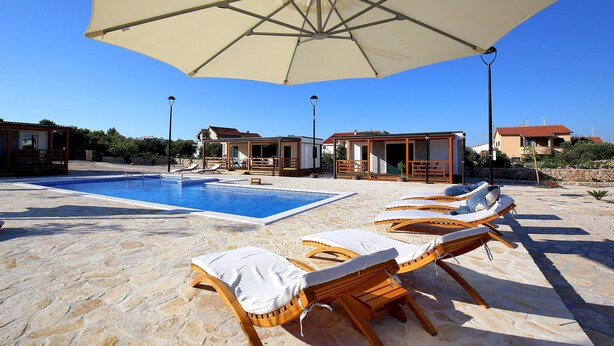 A poolside area with lounge chairs and a large umbrella. - Beautiful home in Murter (Murter)