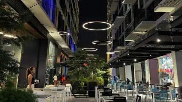 An outdoor dining area with circular light fixtures, a wooden bench, and a row of tables and chairs. - Apartment W/Balcony overlooking downtown (Guatemala city)