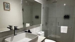 A modern bathroom with a large mirror, a sink, a toilet, and a glass-enclosed shower. - Apartment W/Balcony overlooking downtown (Guatemala city)