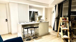 A modern kitchen with a central island, bar stools, and a wooden ladder. - Apartment W/Balcony overlooking downtown (Guatemala city)