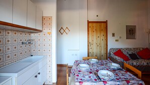 A compact kitchen with a sink and cabinets, a dining table set for four, and a sofa in the living area. - Pet friendly apartment in Tavarone (Tavarone)