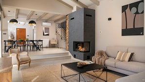 Una sala de estar moderna con chimenea, un sofá, una mesa de centro y un comedor con sillas y una mesa.