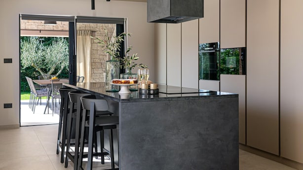 Una cocina moderna con una isla central, taburetes de bar, una chimenea de piedra y vistas al exterior.