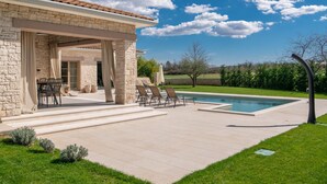 Una casa de piedra con piscina, mobiliario exterior y jardín.