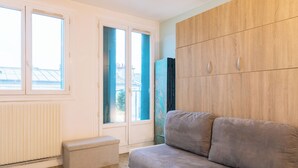A room with a sofa, a bench, and a wardrobe. - Stylish Studio 12 Min from Republique (Paris)