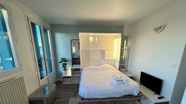 A modern bedroom with a large bed, a TV, and a desk. - Stylish Studio 12 Min from Republique (Paris)