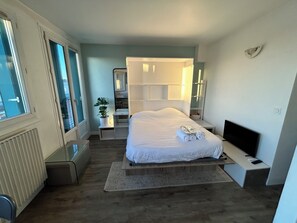 A modern bedroom with a large bed, a TV, and a desk. - Stylish Studio 12 Min from Republique (Paris)