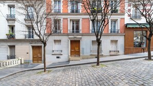 Eine Kopfsteinpflasterstraße mit einer Reihe traditioneller europäischer Gebäude, darunter Holztüren und Balkone mit Metallgeländern.