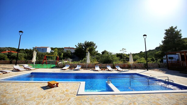 A swimming pool with lounge chairs and a children's play area.