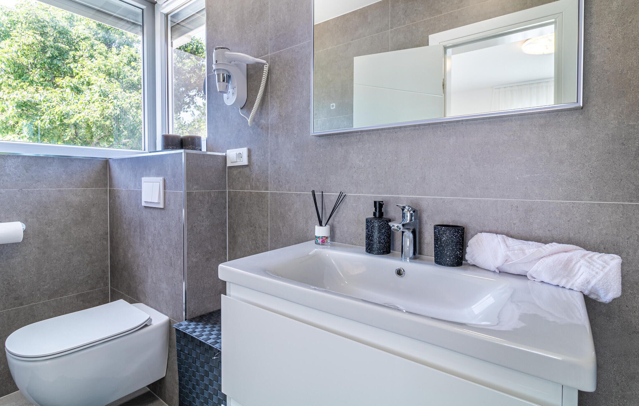 Een moderne badkamer met een badkuip, toilet en een grote spiegel.