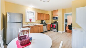 A modern kitchen with wooden cabinets, stainless steel appliances, and a white dining table. - 5 Mi to Dtwn Boston! Family-Friendly Medford Apt (Medford)