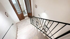 Una escalera con barandilla metálica y suelo de baldosas.