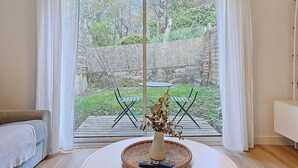 A room with a large sliding glass door leading to an outdoor area with a table and chairs. - Appartement Le Porto, Cosy et Chaleureux ! (Cholet)