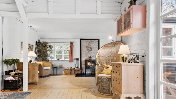 A cozy living room with a fireplace, wicker furniture, and a wooden floor.