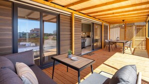 A modern, open-plan living space with a wooden deck, large sliding glass doors, and a cozy seating area.