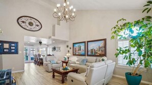 A spacious living room with a chandelier, a large potted plant, and framed artwork on the walls. - Resort Style Vacation Home (El Paso)