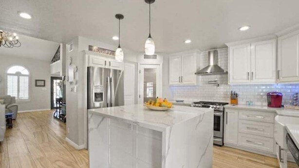 A modern kitchen with white cabinetry, a marble island, stainless steel appliances, and pendant lighting. - Resort Style Vacation Home (El Paso)