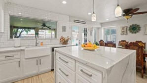 A modern kitchen with white cabinetry, a marble island, and pendant lighting. - Resort Style Vacation Home (El Paso)