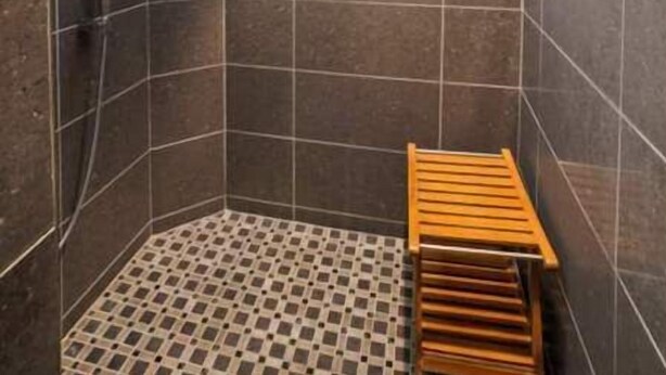 A modern bathroom with a shower area, tiled walls, and a wooden bench. - Resort Style Vacation Home (El Paso)