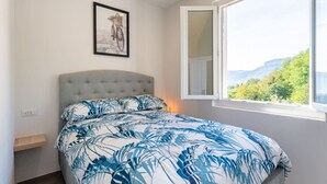 A bedroom with a bed, a framed picture on the wall, and a window with a view of greenery. - * Villa Maximus - Stunning mountain views (Barga)