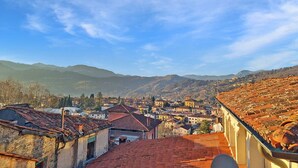 Une ville avec un bâtiment remarquable à toits rouges en premier plan, un ciel bleu dégagé et des montagnes lointaines.