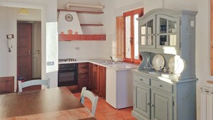 A kitchen with a stove, sink, and cabinets. There is a dining table with chairs. - La Tegola - Old town apartment with amazing views (Barga)