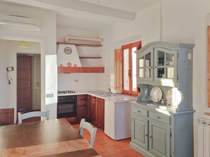 A kitchen with a stove, sink, and cabinets. There is a dining table with chairs.