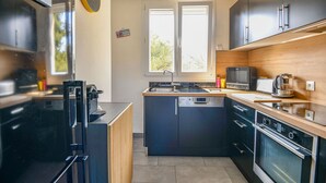 A modern kitchen with a dishwasher, stove, microwave, and a coffee maker. - Bel appart avec balcon et clim près des Calanques (Marseille)