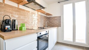 Una cocina moderna con salpicadero de ladrillo, horno empotrado y un ventanal amplio.