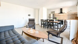 Una sala moderna con un sofá, una mesa de centro de madera y una zona de comedor con sillas y una mesa.