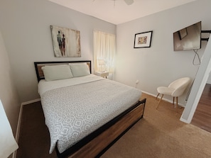 A bedroom with a bed, a chair, a nightstand, a lamp, and artwork on the walls. - Valdosta relax getaway (Valdosta)