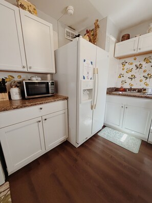 A kitchen with white cabinets, a microwave, a refrigerator, and a water dispenser. - Valdosta relax getaway (Valdosta)