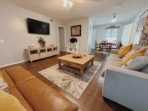 A living room with a sofa, coffee table, TV, and a dining area with chairs and a table. - Valdosta relax getaway (Valdosta)