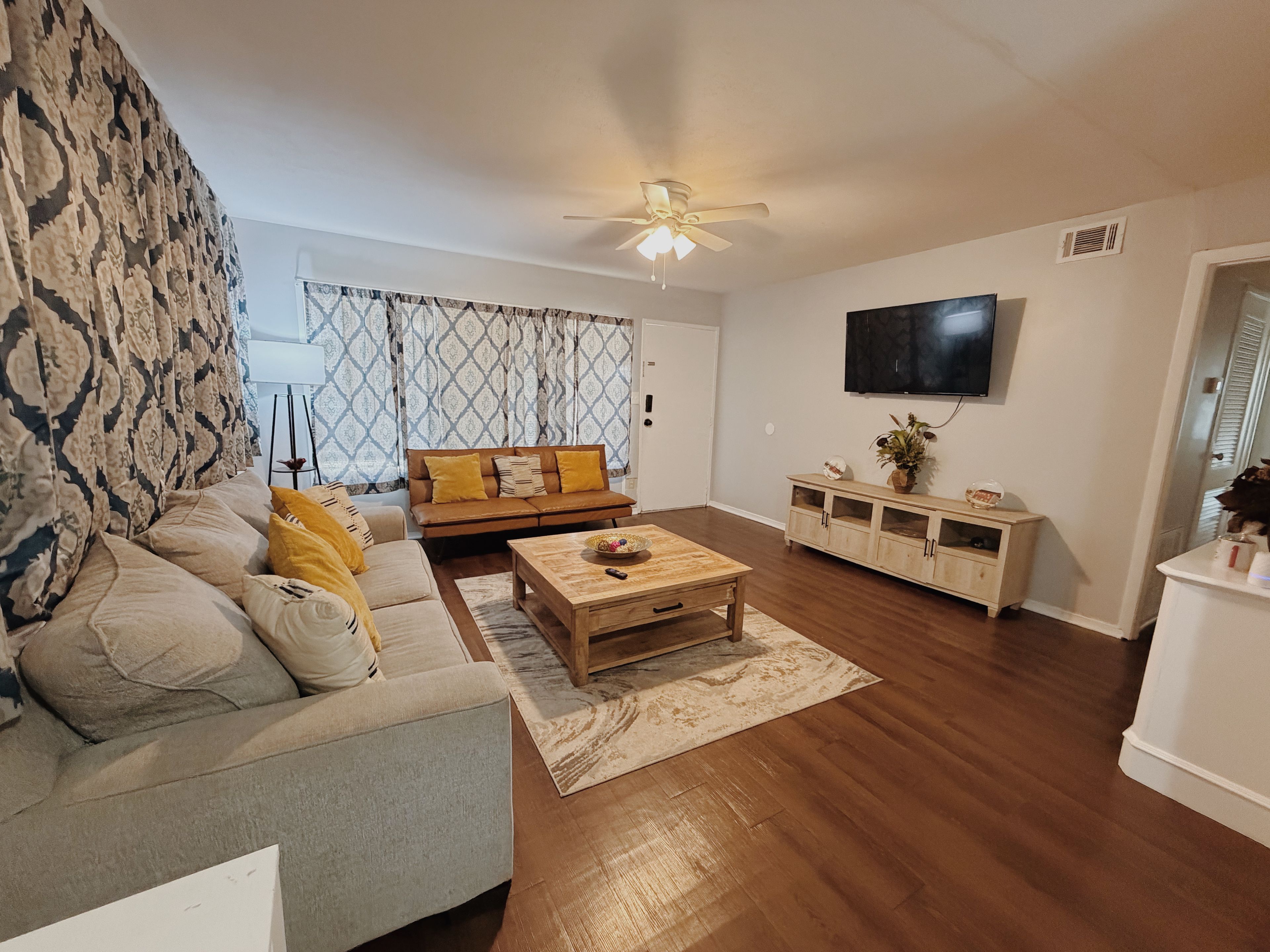 A living room with a sofa, coffee table, and a TV mounted on the wall.
