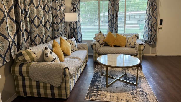 Ein Wohnzimmer mit zwei Sofas, einem Couchtisch und gemusterten Vorhängen.