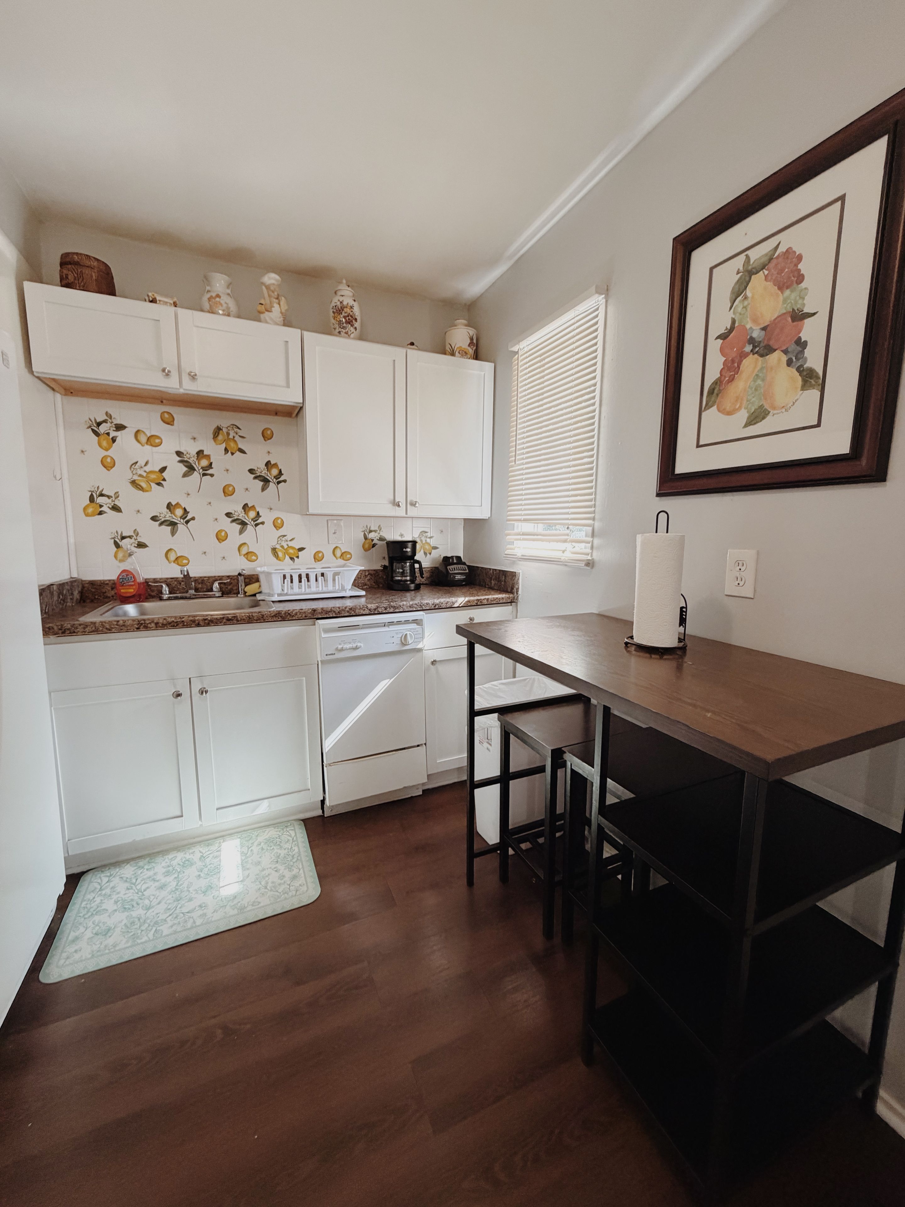 A compact kitchen with white cabinets, a coffee maker, and a dining area with a table and chairs.