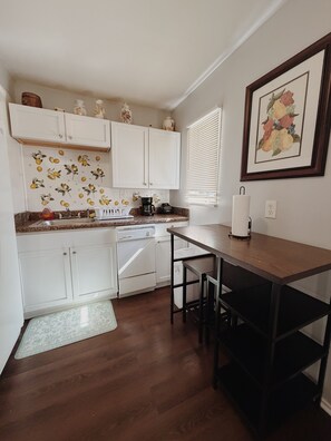 A compact kitchen with white cabinets, a coffee maker, and a dining area with a table and chairs. - Valdosta relax getaway (Valdosta)