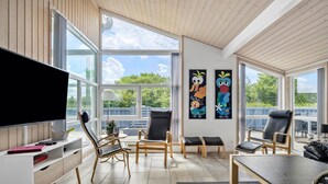A modern living room with large windows, a flat-screen TV, and a dining area. - Amazing home in Tarm with kitchen (Tarm)