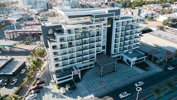 Un hotel moderno de varios pisos con un patio central, rodeado por un estacionamiento y una calle.
