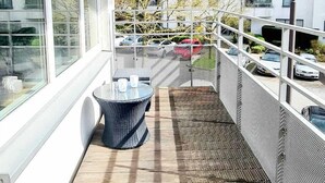 A balcony with a woven floor, a round table with chairs, and a hanging light fixture. - Luxury 1 bedroom flat w parking&balcony (Luxembourg City)