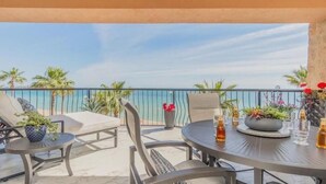 A balcony with a view of the sea, equipped with a round table, chairs, and potted plants. - Dang This Place Fancy / Sonoran Sea / Sandy Beach / Beachfront End Unit (Puerto Peñasco)