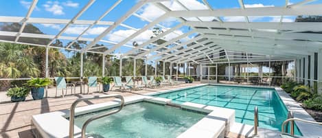 A pool area with a glass ceiling, lounge chairs, and potted plants.