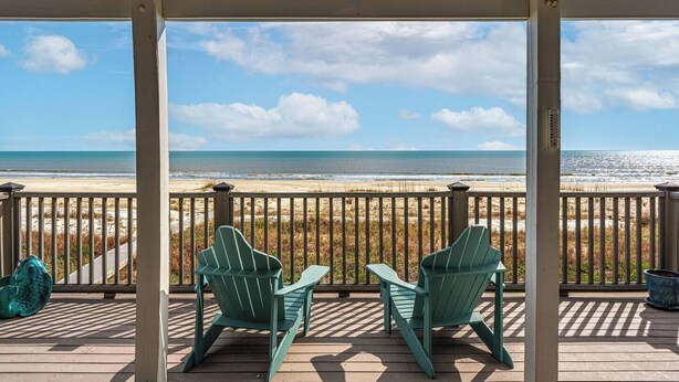 A covered deck with two Adirondack chairs facing a beach. - SunScape & SeaScape: Beachfront, 2 Kitchens, Elevator, Pool/Spa, Pet-Friendly (Port Saint Joe)