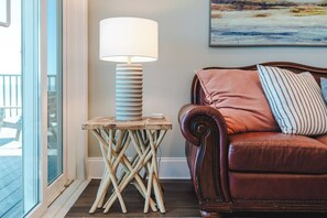 Une pièce chaleureuse avec une petite table en bois, une lampe, un canapé en cuir et un tableau accroché au mur.